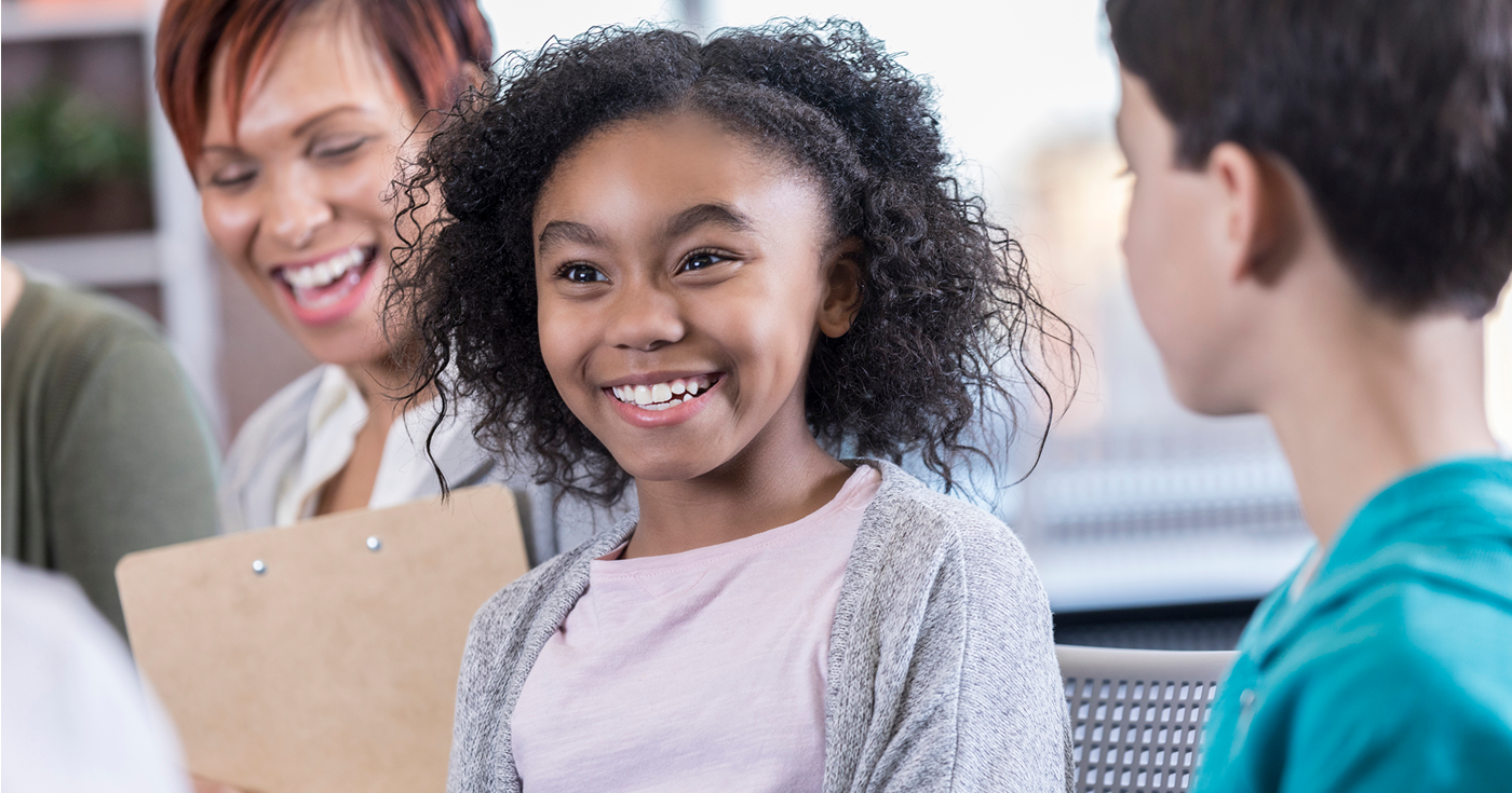 Smiling young girl with curly hair in a casual setting.