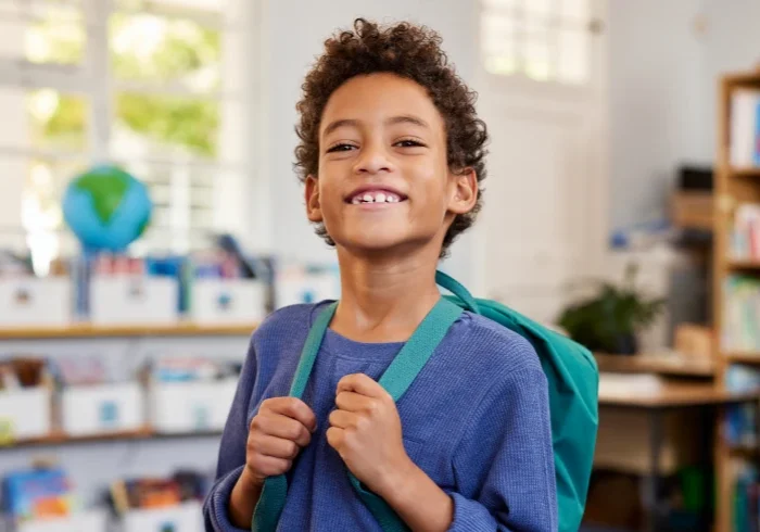 Young boy wearing a backpack indoors
